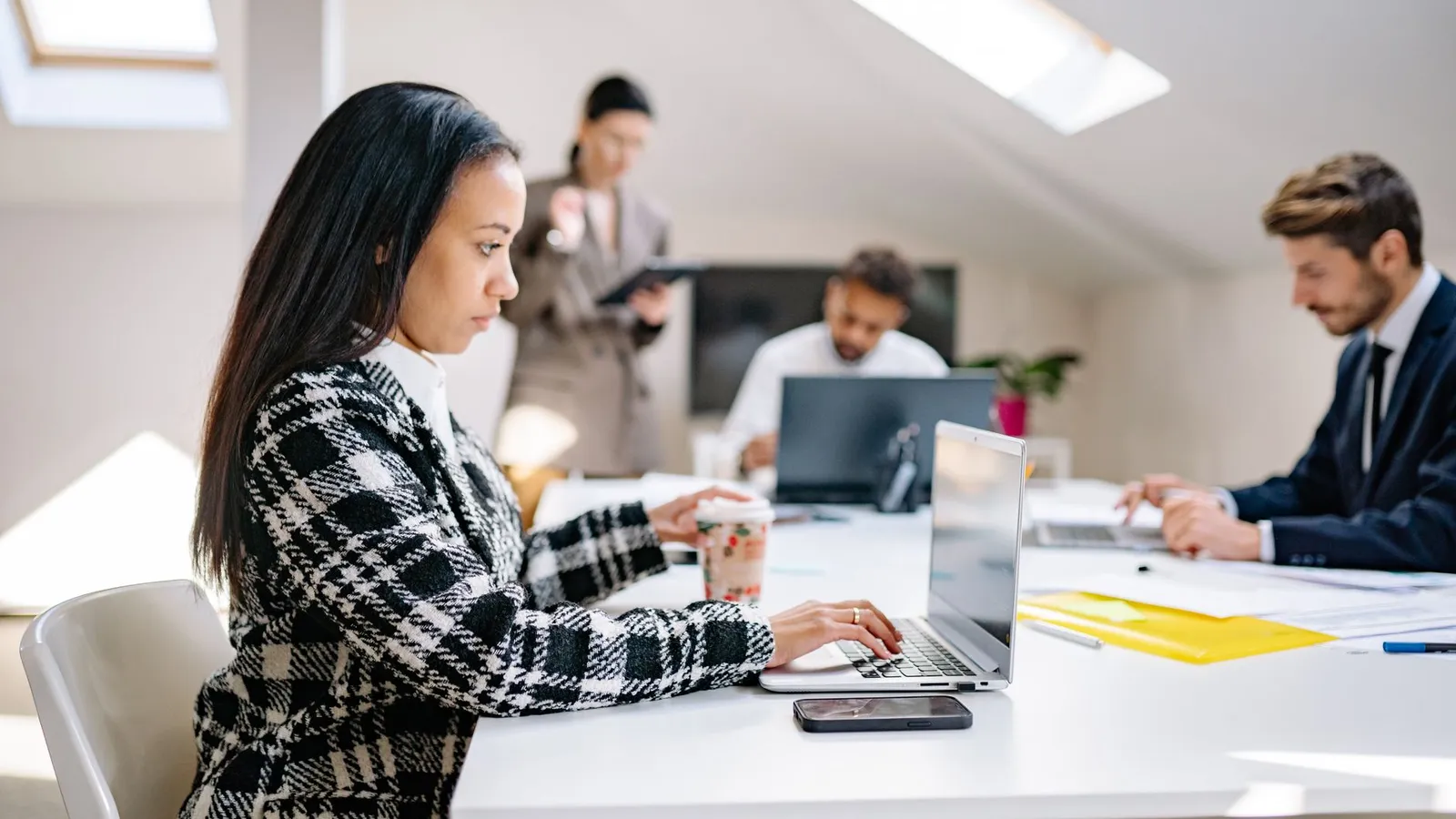 Geschäftsfachleute arbeiten in einer modernen, kollaborativen Büroumgebung mit Laptops.