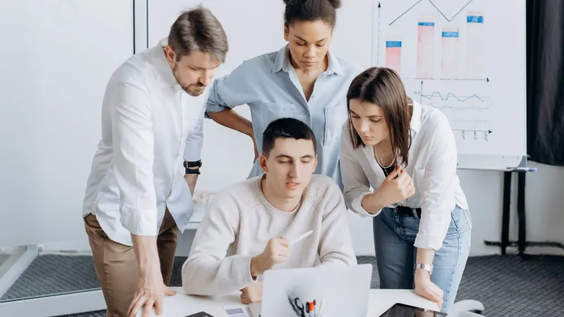 Gruppe von Fachleuten, die in einem Büro-Setting an einem Projekt mit Grafiken zusammenarbeiten.