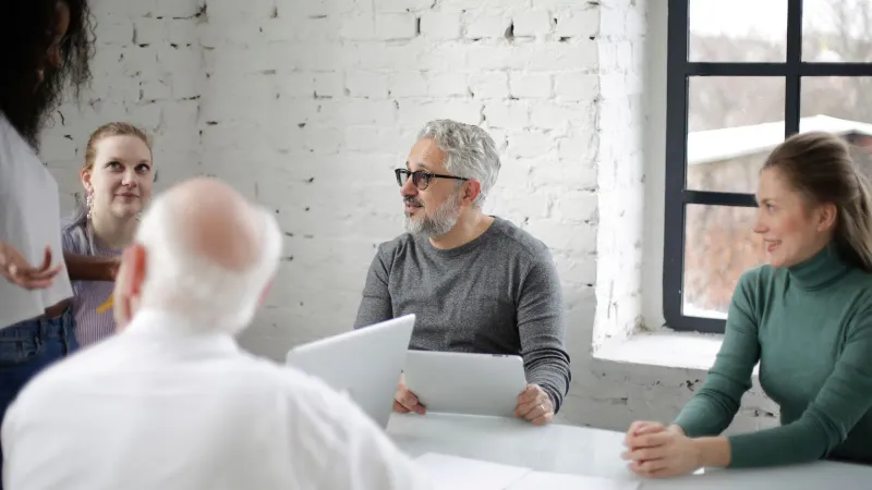 Eine vielfältige Gruppe von Fachleuten in einem modernen Büro, die an einer Brainstorming-Sitzung teilnehmen und Teamarbeit sowie Strategien fördern.