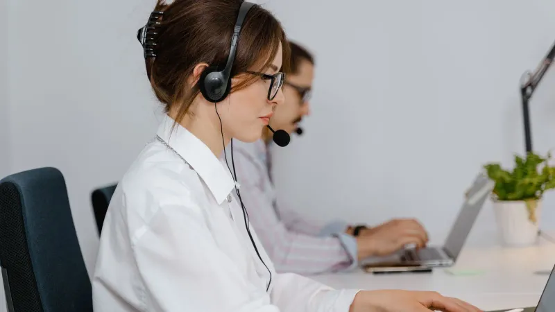 Kundenservice-Agenten arbeiten in einem Callcenter mit Headsets und konzentrieren sich darauf, Unterstützung zu bieten.