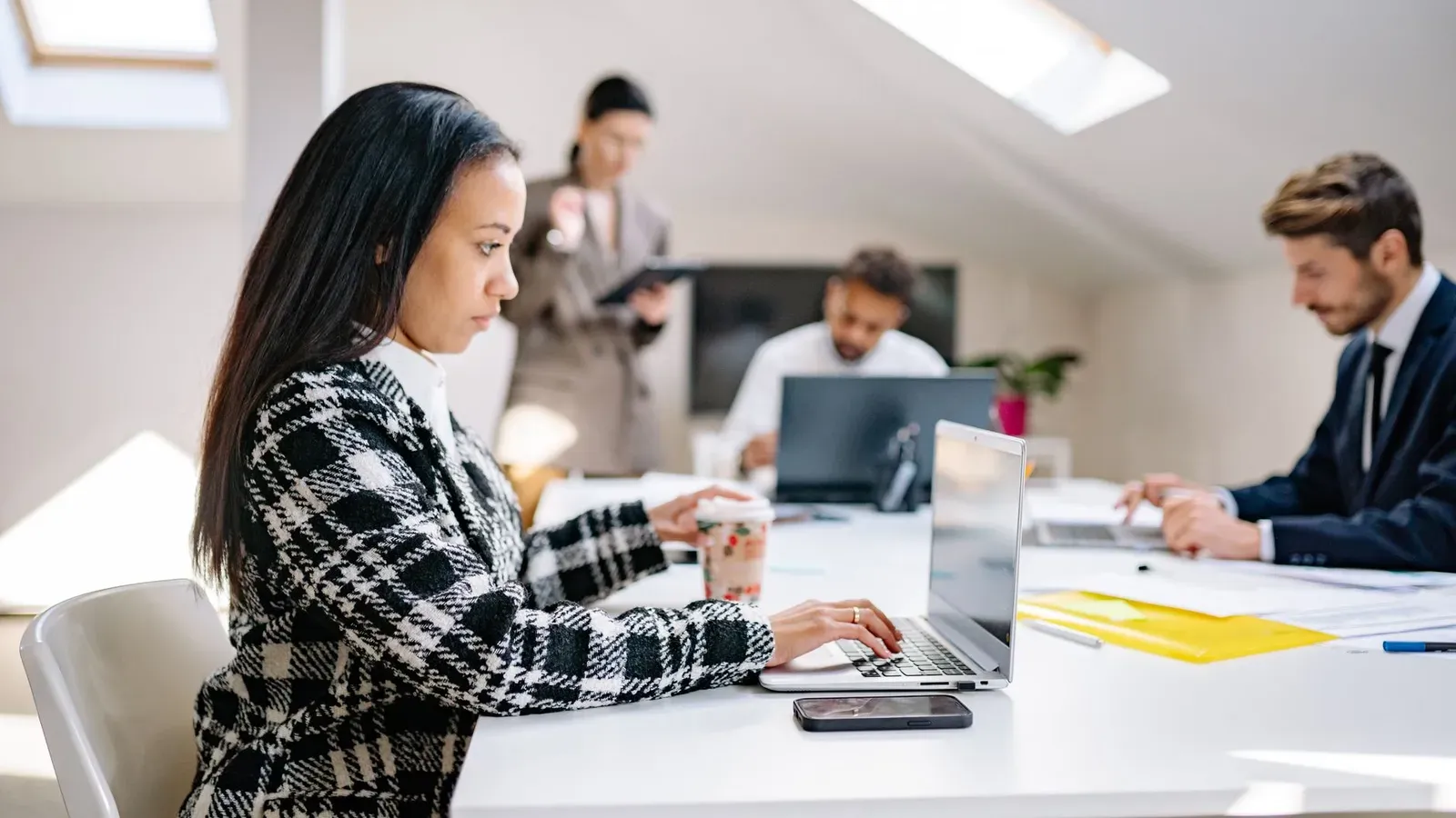 Geschäftsfachleute arbeiten in einer modernen, kollaborativen Büroumgebung mit Laptops.