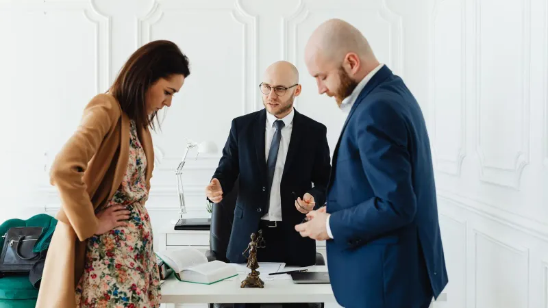 Ein Anwalt trifft sich mit Mandanten, um rechtliche Angelegenheiten in einem professionellen Büroumfeld zu besprechen.