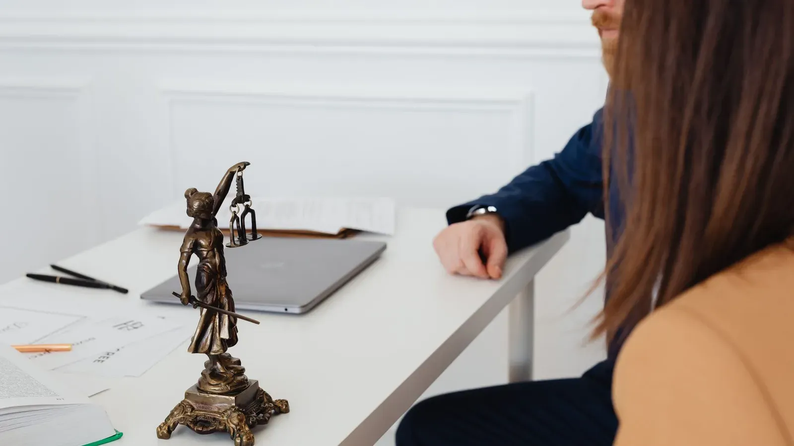 Professionelle Umgebung mit Anwälten und einer Lady Justice Statue, die rechtliche Dokumente besprechen.