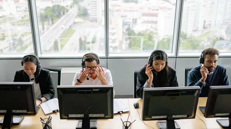 Gruppe vielfältiger Callcenter-Mitarbeiter, die in einem modernen Büroumfeld an Computern arbeiten.