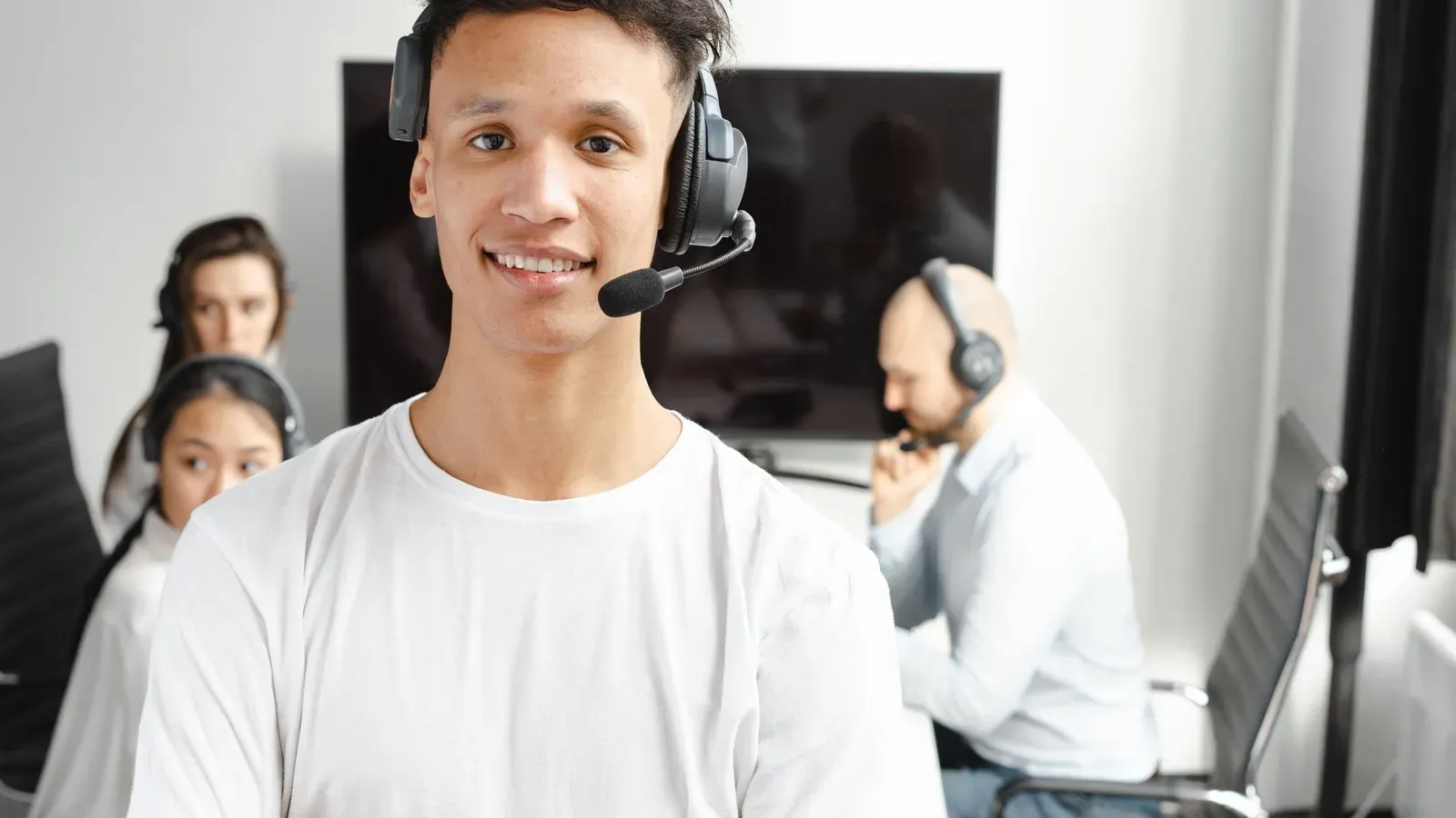 Lächelnde Agenten mit Headsets arbeiten in einer hellen, modernen Büroumgebung.