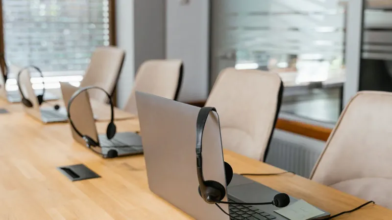 Reihe von Laptops mit Headsets in einer modernen Büroumgebung, bereit für die Kommunikation.
